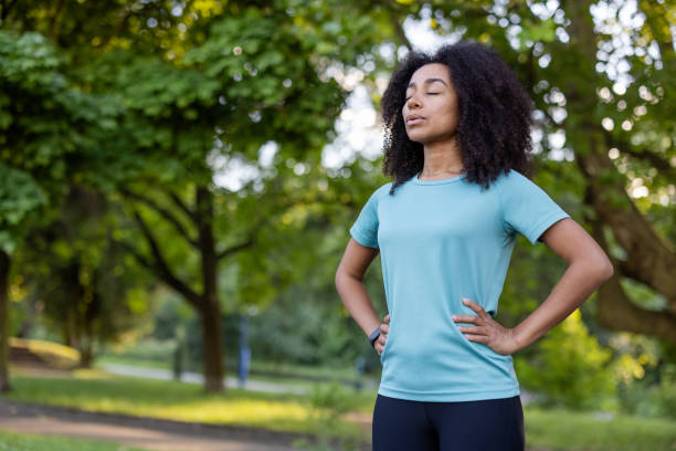 istock Confident African American female in a park setting engaged in mindfulness exercise, standing with eyes closed. Portraying fitness, relaxation, and inner peace in an outdoor green environment 2174754891