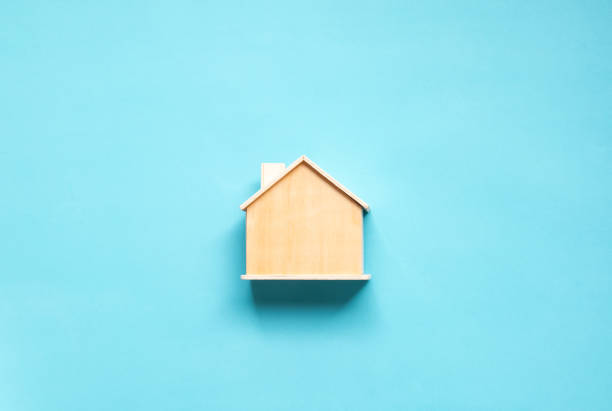 istock Wooden house model placed on a blue background, representing real estate, home design, or construction themes 2174755111
