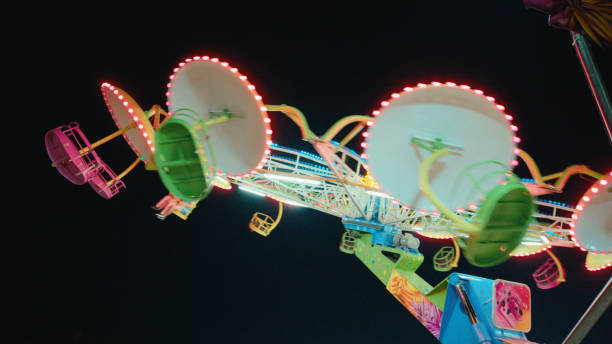 Fair during a summer sunset with illuminated fairground attractions in various colors in the park in Zwolle, Netherlands, during the summer fair. Long exposure photo showing the motion of the fair ride.