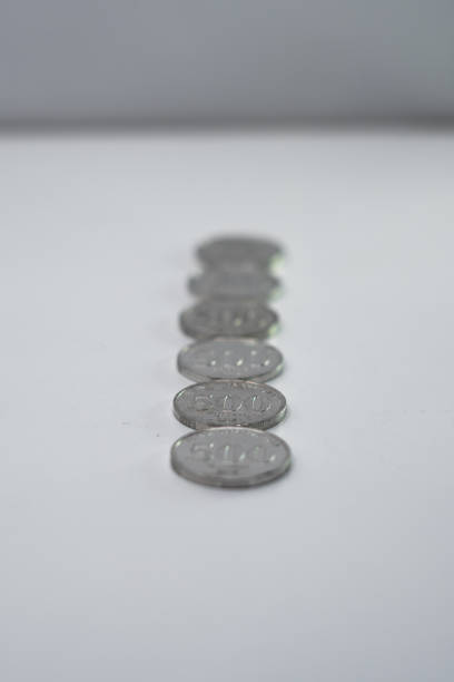 Heaps of money or pile of gold colored golden currency coins arranged as mountain or set or stacks of abundant money placed on a wooden surface over beige gray colored horizontal background with copy space