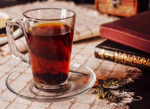 istock Steaming cup of tea with books and dessert on tablecloth 2174769822