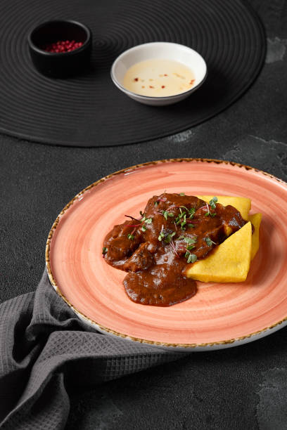 istock Rustic Polenta with Braised Beef Cheeks on Pink Plate in Dim Lighting for Noir Cuisine Photography 2174769869