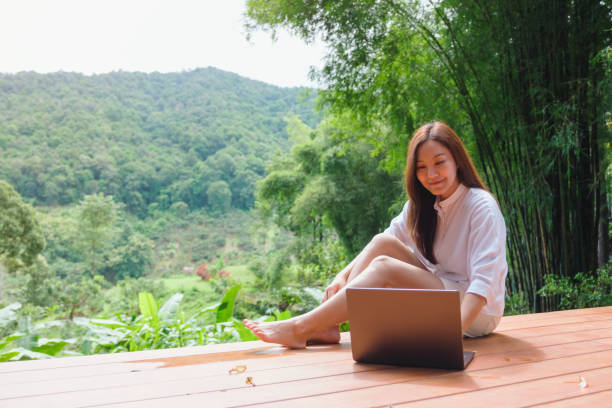 istock Portrait image of a woman using and working on laptop computer while sitting on balcony with a beautiful nature view 2174777472