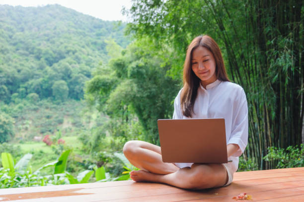 istock Portrait image of a woman using and working on laptop computer while sitting on balcony with a beautiful nature view 2174777479