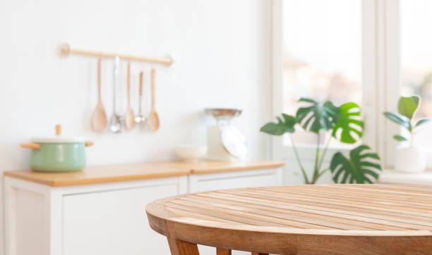 Round kitchen table in front of blurred kitchenware, furniture and window interior background