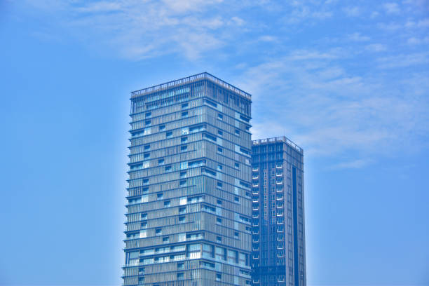 Indonesia, Jakarta, September 26, 2024:  A tall glass-walled office building towers against a backdrop of sky and clouds.