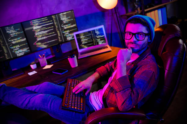 istock Photo of smiling cool guy dressed glasses hat thinking fulfil coding tasks indoors workstation workshop home 2174808499