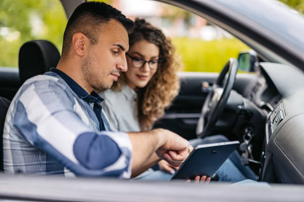 Driving Instructor Showing His Female Student Driving Test Results On A Tablet