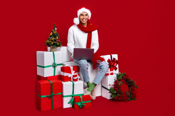istock Full body portrait of handsome guy sit pile stack newyear giftbox use netbook isolated on red color background 2174826126