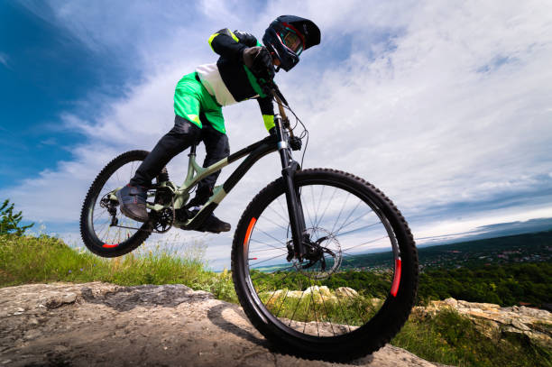 istock cyclist rides on his front wheel. Biker balances while riding a mountain bike. Risky riding on one wheel, performing a stunt 2174832216