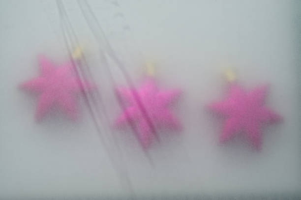 Three purple Christmas balls covered with transparent paper, blurred background. New Year's background. For design.