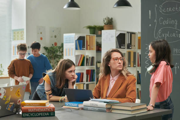 istock Teacher Talking to Girls in School Library 2174840027