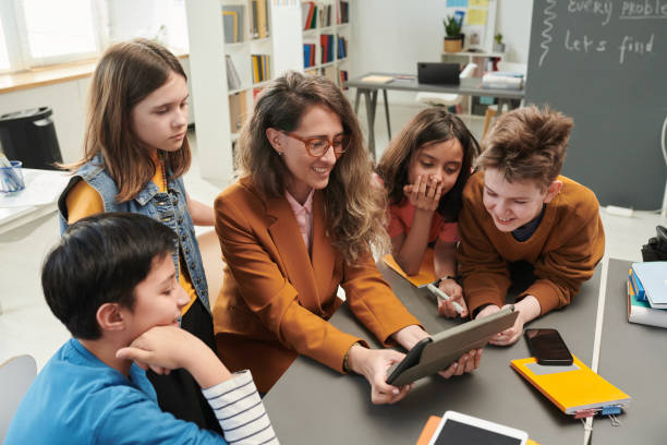 istock Smiling Female Teacher using Tablet with Kids 2174840103