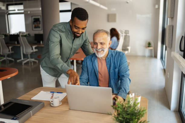 istock Colleague assisting a senior man with laptop work 2174846834