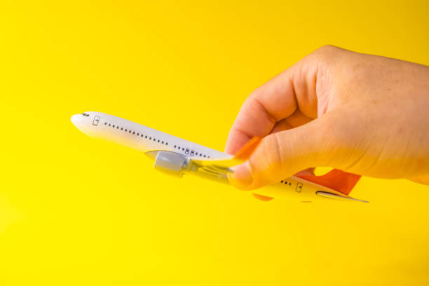 istock Male hand holding an airplane on yellow background 2174851937