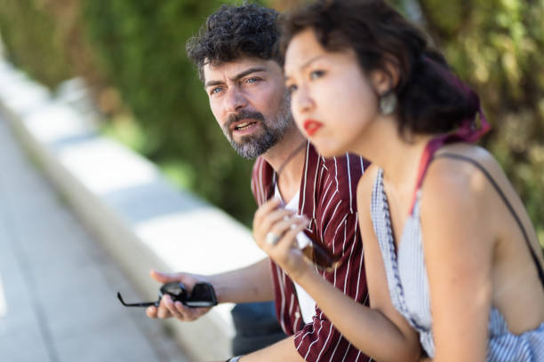 Two friends engage in a casual conversation outdoors on a sunny day, showcasing curiosity and communication.