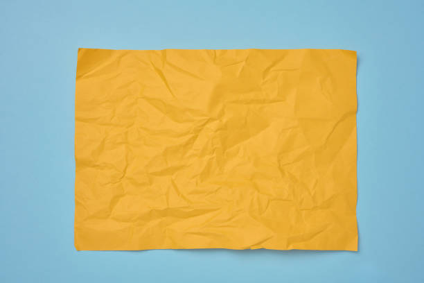 A close-up, top-down shot showcases the crinkled and uneven texture of yellow paper. Background concept.