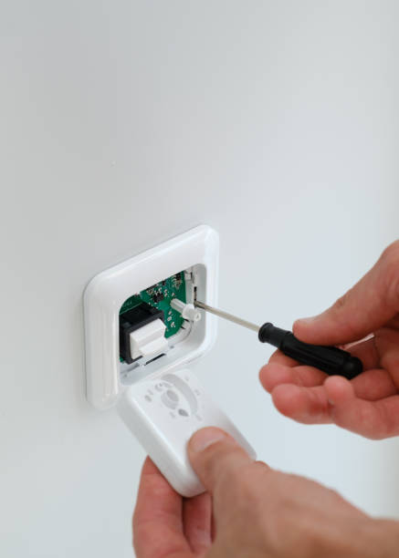 istock Electrician with screwdriver repairing power socket in room 2174884193