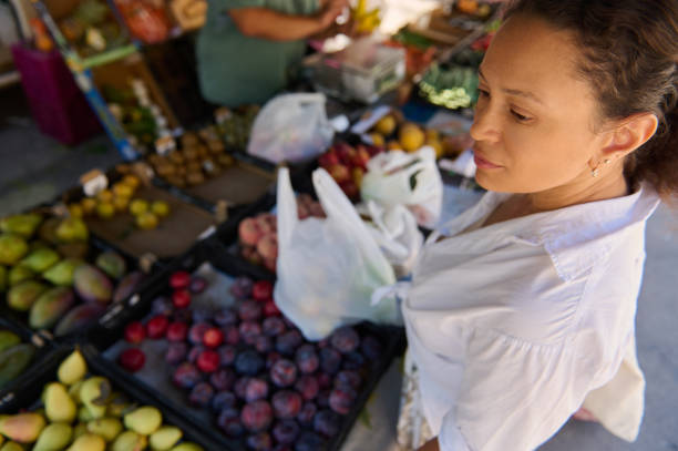 Woman shopping at a vibrant fruit market with fresh produce on display in colorful baskets
