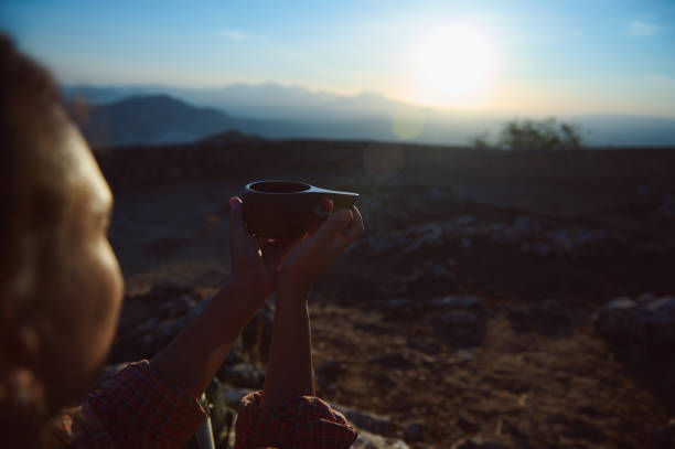 istock Person holding a cup at sunrise in a tranquil mountain setting, capturing the serene moment and the beauty of nature. 2174884861
