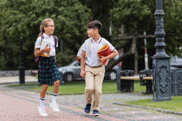 istock Joyful kids chatting after school while walking outdoors through a sunny park 2174884892