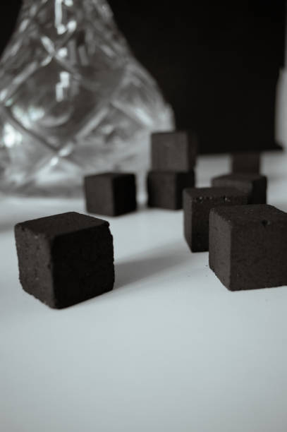 istock Hookah with coals on white surface on black background. Black charcoal cubes lay randomly. Space for text. Soft focus. 2174885066