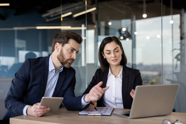istock Business colleagues discussing project details in modern office setting using laptop and tablet 2174886695
