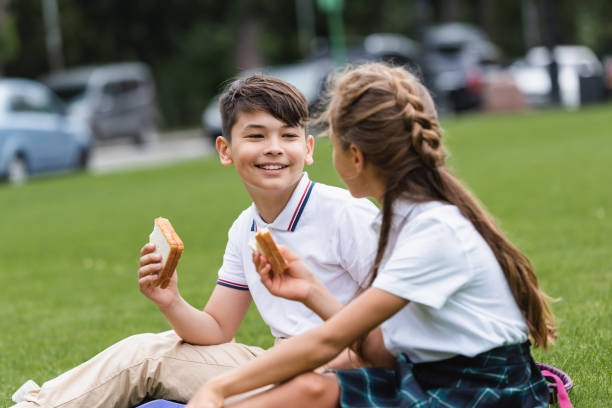 istock Kids enjoy a sunny afternoon outdoors sharing snacks and laughter after school 2174887348
