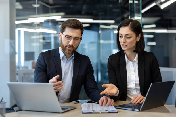 istock Professional business meeting with two colleagues discussing project on laptops in modern office setting 2174889836