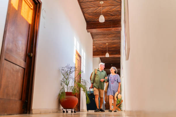 istock Senior couple talking and walking with suitcase at hotel 2174899585