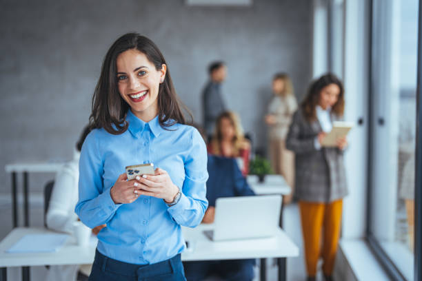 istock Casually dressed young woman using her mobile phone to read something at work. 2174899802