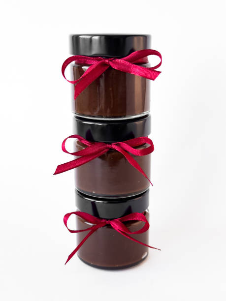 Homemade chocolate spread jars with red ribbon on white background