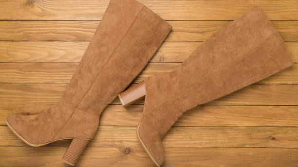 istock Brown suede boots on wooden background, top view 2174901350