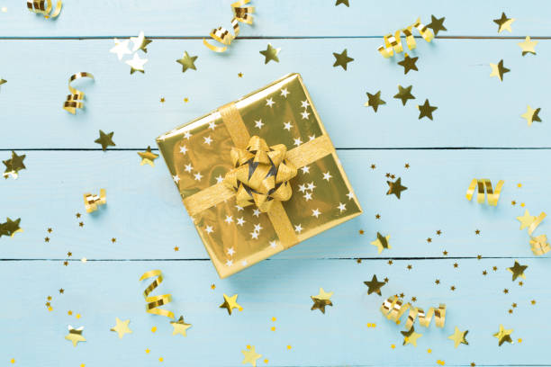 istock Golden gift boxes and confetti on wooden background, top view 2174901508