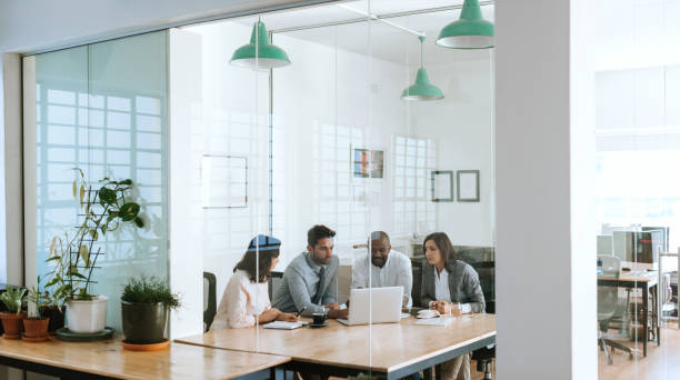 istock Diverse businesspeople using a laptop together in an office boardroom 2174902095