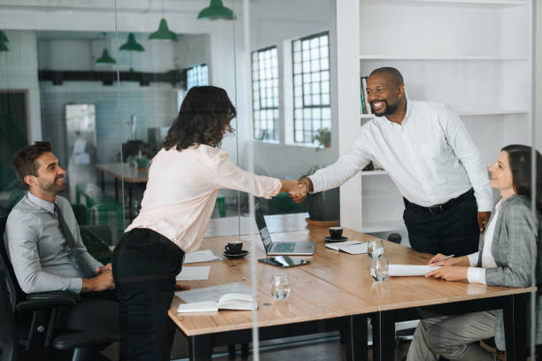 istock Smiling businessspeople standing in a boardroom shaking hands together 2174902646