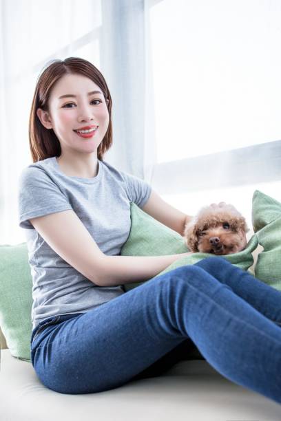 istock A young woman is sitting on a couch with a small dog 2174903208