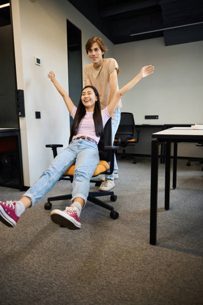 istock Guy is pushing his colleague in an office chair 2174904284