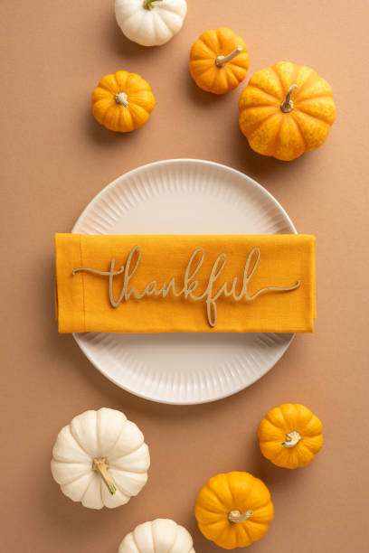 istock A table vertical setting featuring a thankful message on a napkin surrounded by small orange and white pumpkins, highlighting a Thanksgiving Day theme 2174905643