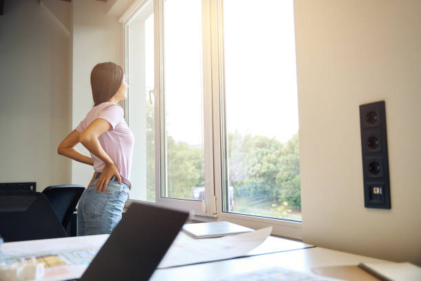istock Creative woman is standing by large window in the office 2174905878