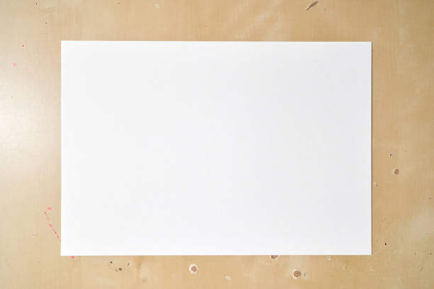 Blank white paper on wooden desk with subtle texture for creative background