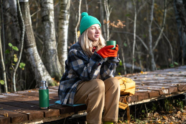 istock Time alone. Relaxed middle aged woman enjoy calm weekend in fall park meditative drinks thermos tea. 2174906014