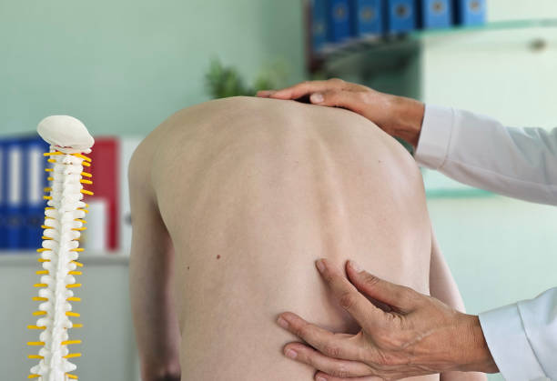 Orthopedist examines the spine, posture, and spinal deformities of teenage patient Orthopedist examines the spine, posture, and spinal deformities of teenage patient. Teenage boy visiting paediatrician for annual preventive physical kyphosis stock pictures, royalty-free photos & images