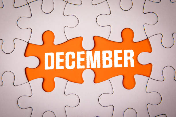 istock DECEMBER. White puzzle pieces and text on an orange background 2174910360