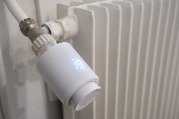 istock Connected thermostatic head, mounted on a white cast-iron radiator, indicating 19 degrees celcius. 2174911500