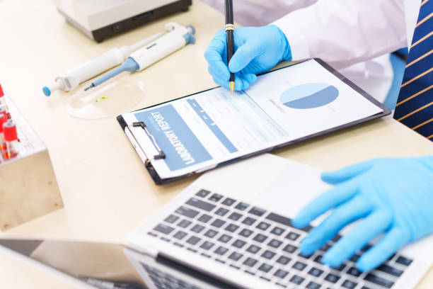 istock Two Asian scientists in lab coats sit at a table in a laboratory, examining samples through a microscope. The room is equipped with scientific tools, liquids, and chemistry materials. 2174914178