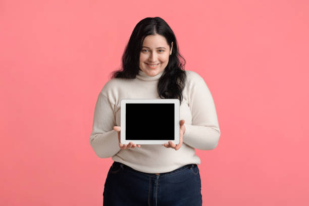 istock Happy Plus Size Girl Demonstrating Digital Tablet With Black Blank Screen 2174918349