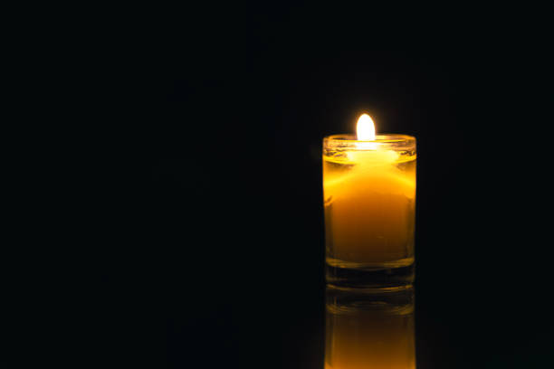 A close-up view of warm candlelight shining through a glass lantern with star patterns. The golden hues and soft glow create a dreamy and magical holiday ambiance.