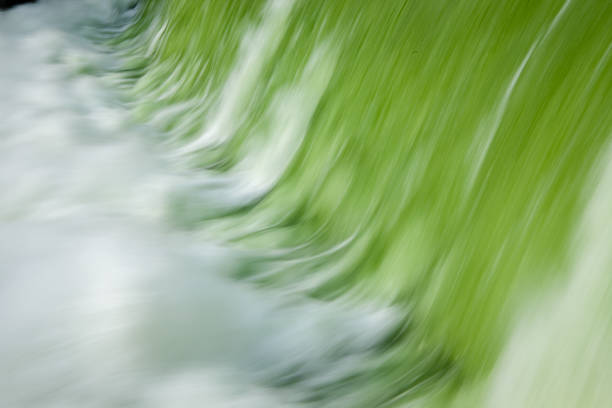 Abstract photograph of water cascading over a weir, creating a beautiful pattern of green and white