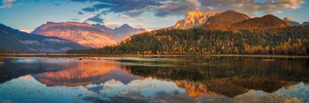 istock Sunlight reflecting in calm lake surrounded by forest and mountains 2174919804